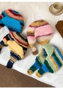 Flat lay of colorful striped mohair earflap hats in vibrant knit patterns on white fabric