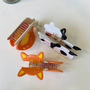 Detailed view of three acetate hair claws featuring fox, cow, and ear designs