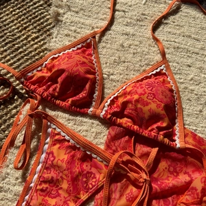 Détail du bikini floral avec imprimé orange et texture de bordure en dentelle ondulée