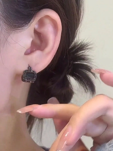 Close-up of elegant square black rhinestone hoop earrings worn on model's ear