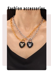 Détail de chaînes à maillons or et argent avec pendentif cadenas cœur noir et pierre zircon