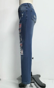 Dettaglio di jeans blu scuro usurati con strappi e inserti con stampa leopardata rosa