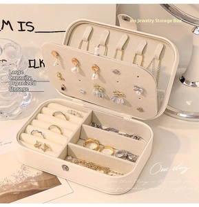Detailed interior of a beige faux leather jewelry box with earring plate and ring slots