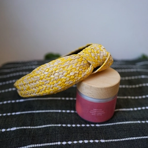 Close-up of woven raffia headband showing yellow and natural straw texture details