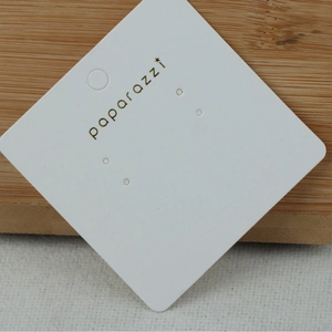 Square white paper jewelry display card for earrings with star logo on wood background