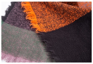 Detail shot of multicolor plaid wool poncho featuring vibrant fringe edges and soft texture
