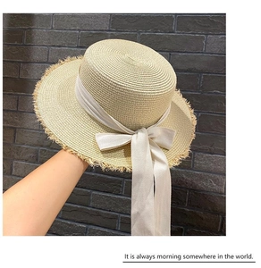 Close-up of beige boater hat showing woven straw texture and stylish silk ribbon bow