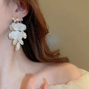 Macro de boucles d'oreilles pétales blancs avec cristaux et pompons sur un mannequin