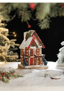 Détail d'une maison de Noël en bois avec toit enneigé et lumière LED chaude et douce