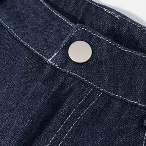 Vue macro de la taille d'un jean bleu foncé avec bouton en métal et coutures blanches