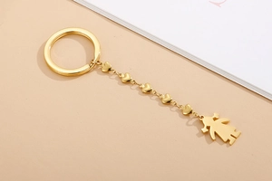 Close-up of golden metal keychain featuring heart-shaped links and a girl silhouette charm