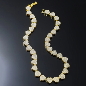 Luxury gold Cuban link necklace with iced out heart charms on black reflective background