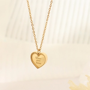 Collier doré avec pendentif cœur gravé Love You More sur fond beige romantique