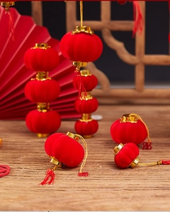 Mini red flocked lanterns with golden caps and red tassels on wooden table setting