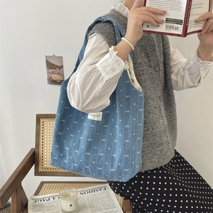 Grand sac cabas en jean bleu avec nœuds blancs porté par une étudiante sur une chaise