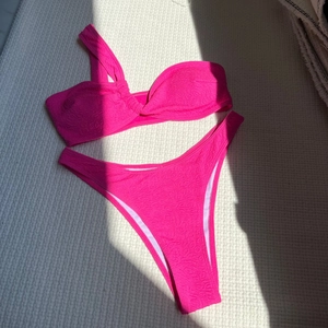 Detailed view of pink one-shoulder bikini with embossed jacquard fabric texture