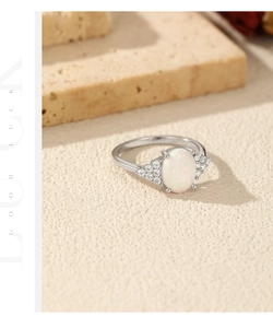 Detailed view of silver ring featuring oval opal and accent stones on textured stone