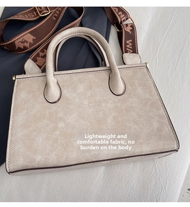 Close-up of cream textured faux leather tote bag with stylish wide patterned shoulder strap