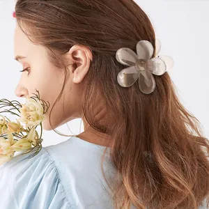 Detail of a large champagne translucent flower hair claw clip on long wavy hair