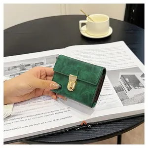 Close-up of a dark green vintage texture mini wallet with a gold clasp being held