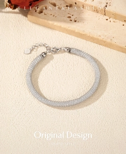 Macro shot of silver mesh woven bracelet featuring a lobster clasp and tiny heart tag