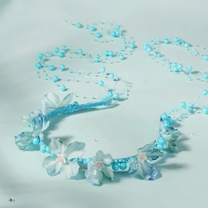 Detail of blue fabric flower headband with hanging pearl tassels and satin wrap
