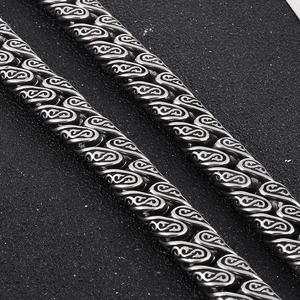 Detailed macro view of punk style silver Cuban chain necklace with vintage engraved patterns