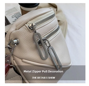 Close-up of beige lychee grain leather bag with dual silver metal zippers and minimalist hardware