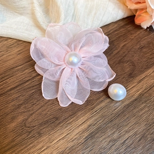 Detail of pink chiffon flower earring with large white pearl on textured wood