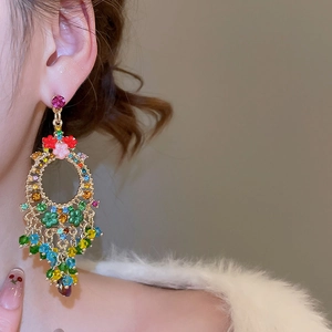 Close-up of sparkling floral crystal tassel earrings worn by a model in warm light