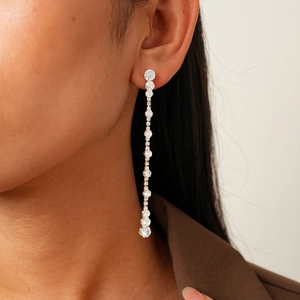 Macro shot of long silver tassel earrings with round crystals on female model