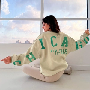 Détail du sweat beige oversize avec inscription Chicago et New York verte sur le dos