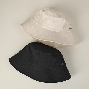 Detail of cotton linen bucket hats with checkered texture and small metal logo plates