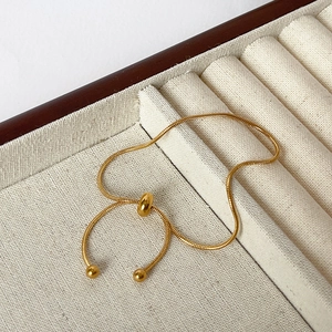 Close-up of golden snake chain bracelet with adjustable slide clasp on a display tray