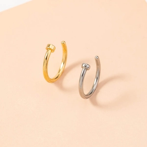 Macro view of gold and silver nail-shaped U-shaped non-pierced nose rings and cuffs