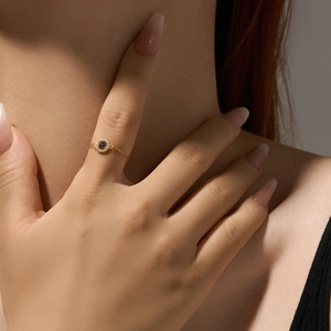 Detail of a minimalist gold chain ring with blue stones and white zircon crystals