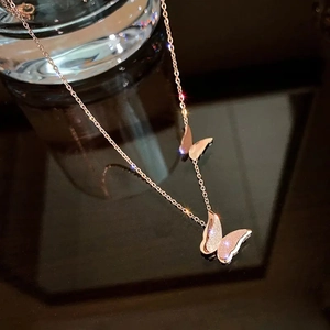Detailed macro of rose gold titanium butterfly pendant with glitter finish and fine O-chain