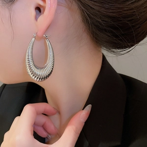 Detailed view of silver U-shaped hoop earring with ribbed texture on professional model