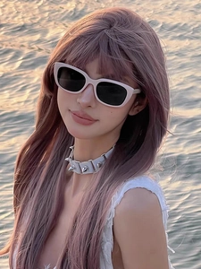 Nahaufnahme der rosa Cat-Eye-Sonnenbrille und des weißen Nietenhalsbands bei Sonnenuntergang