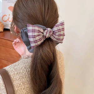Detail view of the purple grid fabric bow hair scrunchie worn on a high ponytail