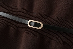 Detail of dark brown knitwear with a thin black leather belt and golden metal buckle