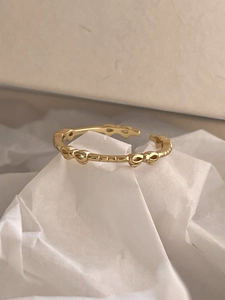 Detailed close-up of golden bow-shaped open ring with elegant knot textures on paper