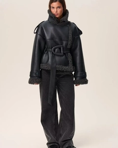 Detail of black leather coat featuring thick curly faux fur trim and cinched waist belt