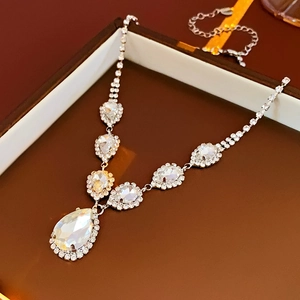 Détail du collier avec pendentif goutte en cristal argenté sur un écrin marron