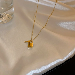 Collana in acciaio al titanio dorato con ciondoli a lucchetto e chiave su seta elegante