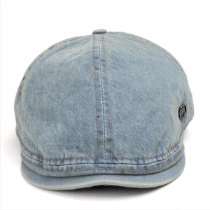 Macro detail of washed light blue denim fabric texture and round metal buckle on ivy cap