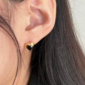 Close-up of a model wearing a gold heart stud earring with a black gemstone inlay