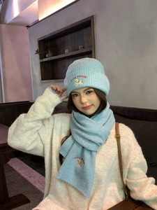 Detail view of a light blue knitted hat and scarf set with cute puppy embroidery.