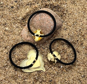 Detailed view of elastic hair ties with gold diamond, heart, and round metal charms