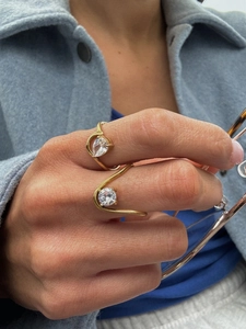 Detail of model wearing gold zircon rings with wavy bands and pear-shaped stones